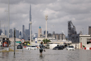 A person walks in flood water caused by heavy rains, with the Burj Khalifa tower visible in the background, in Dubai, United Arab Emirates, April 17, 2024 (Photo: REUTERS/Amr Alfiky).