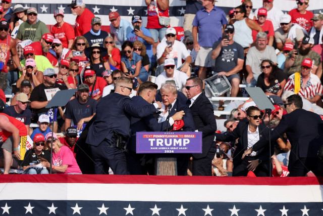 Republican presidential candidate and former U.S. President Donald Trump is assisted by U.S. Secret Service personnel after he was shot in the right ear during a campaign rally at the Butler Farm Show in Butler, Pennsylvania, U.S., July 13, 2024 (REUTERS/Brendan McDermi).