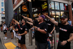 Members of the Goyim Defense League – wearing shirts with the words “Pro White” on the front and “Whites Against Replacement” on the back – make Nazi salutes as flags displaying swastikas are held by other members of the group on Lower Broadway in Downtown Nashville, Tenn., Sunday, July 14, 2024.