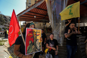 A pro-Iranian Hezbollah supporter, holding a poster that reads: "We will not abandon the weapons" attends a mass rally to mark Ashoura, commemorating the martyrdom of the Prophet Muhammad grandson Hussein. July 6, 2025, Beirut, Lebanon. Photo: ZUMA Press Wire via Reuters Connect