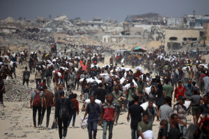 Palestinians walk with sacks of flour delivered after trucks carrying humanitarian aid enter northern Gaza on July 27, 2025, coming from the Zikim border crossing. (Photo by Reuters/Majdi Fathi/NurPhoto)