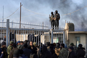 Members of the Syrian government security forces stand guard as a group of detainees gather at al-Hol camp after the government took control of it following the withdrawal of Syrian Democratic Forces (SDF), in Hasaka, Syria, January 21, 2026. Photo: Reuters Connect by Khalil Ashawi