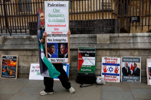 A person holds a sign urging people to not to vote for the Conservative and Labour parties and pro-Palestinian sign amid the Israel-Hamas conflict, outside the Houses of Parliament in Westminster, London, Britain, July 3, 2024. (Photo: REUTERS/Clodagh Kilcoyne)