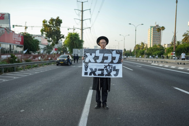 An ultra-Orthodox protester holds a sign that reads, "To jail, not to the army," during a demonstration against the drafting of ultra-Orthodox Jews to the Israeli army, on highway 4 outside of Bnei Brak, June 20, 2024. (Photo: Erik Marmor/Flash90)