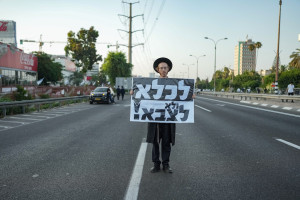 An ultra-Orthodox protester holds a sign that reads, "To jail, not to the army," during a demonstration against the drafting of ultra-Orthodox Jews to the Israeli army, on highway 4 outside of Bnei Brak, June 20, 2024. (Photo: Erik Marmor/Flash90)