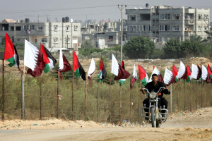 Member of Hamas security forces rides a motorcycle next to Palestinian and Qatar flags during preparations for the celebratory reception of Qatar's Emir Sheik Hamad bin Khalifa al-Thani, in Khan Younis in the southern Gaza Strip on October 22, 2012. The emir of pro-Western Qatar will become the first head of state to enter the blockaded Gaza Strip on Tuesday, in a high-profile visit breaking the isolation of the Iranian-backed Islamist movement Hamas that seized power in 2007. Photo by Abed Rahim Khatib / Flash 90