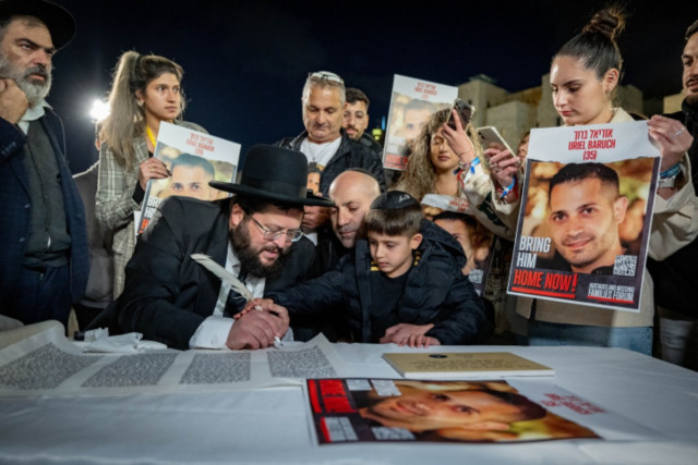 The son of Uriel Baruch write the finishing letters in a new Torah Scroll dedicated to the return of the hostages and in memory of the civilians and soldiers killed in war, at the Western Wall in Jerusalem's Old City, November 21, 2023 (Photo: by Yonatan Sindel/Flash90).