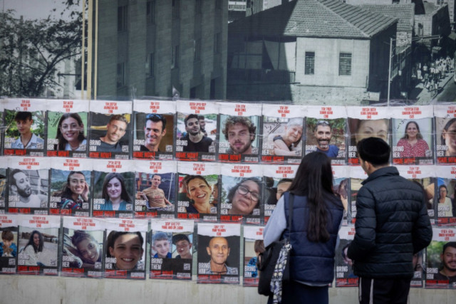 People walk next to pictures of civilians held hostage by Hamas terrorists in Gaza, and some who were released in a deal between Israel and Hamas, in Jerusalem, November 22, 2023 (Photo: Yonatan Sindel/Flash90).