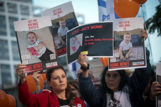 Israelis hold photographs of the Bibas family, and orange balloons, at a press conference calling for the release of 10 month old Kfir, 4 year old Ariel, and their parents Shiri and Yarden Bibas. at "Hostage Square" in Tel Aviv, November 28, 2023. Photo by Miriam Alster/Flash90