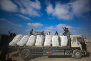 Armed Palestinians sit on trucks carrying humanitarian aid near the Zikim border crossing between Israel and Beit Lahia in the northern Gaza Strip, June 25, 2025. Photo by Ali Qariqa/Flash90