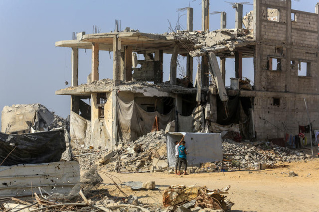 Palestinians walk past buildings destroyed in the recent war, in the Jorat al-Luth area, located between Rafah and Khan Younis in the southern Gaza Strip, November 10, 2025. Photo by Abed Rahim Khatib/Flash90