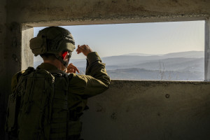 An Israeli soldier looks on as smoke rises in southern Lebanon following an Israeli airstrike, seen from the Israeli side of the border, November 22, 2025. Photo by Ayal Margolin/Flash90
