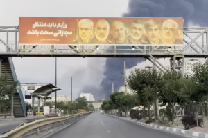 Illustration: Billboard in Iran featuring assassinated IRGC commanders and a message threatening retaliation against Israel, as thick smoke rises in the background following Israeli air strikes. (Screenshot)